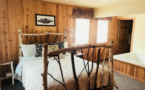 queen size wooden bed with jacuzzi in cabin accommodation