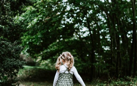 young girl walking on open path in wooded area in fall