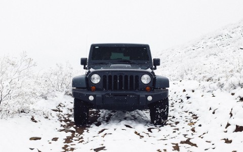black jeep off roading on snow coated dirt path