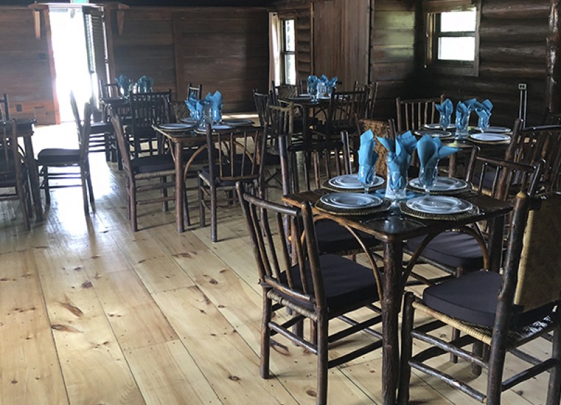 log cabin dining room with wooden floors and wooden chairs, tables dressed for dinner