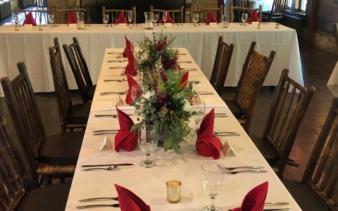 log cabin dining area decorated for a wedding with simple chic white, red, and evergreen decorations