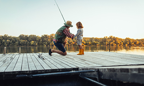 Man teaching a young kid how to fish