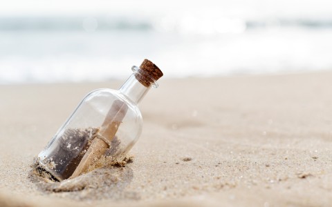  glass bottle with a paper inside in the sand