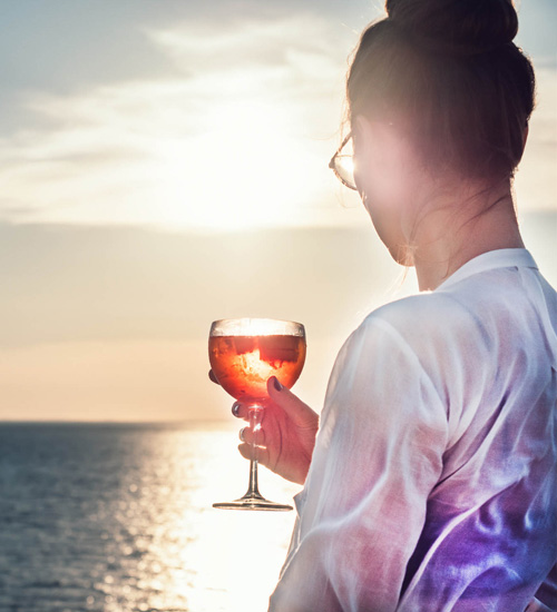 lady wearing glasses holding a glass of cocktail looking to the view