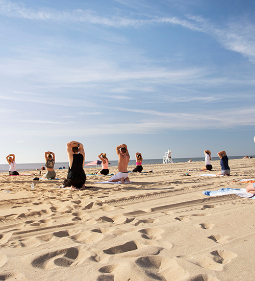 many people doing yoga on the beach