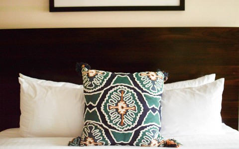 a guest bed with a teal throw pillow