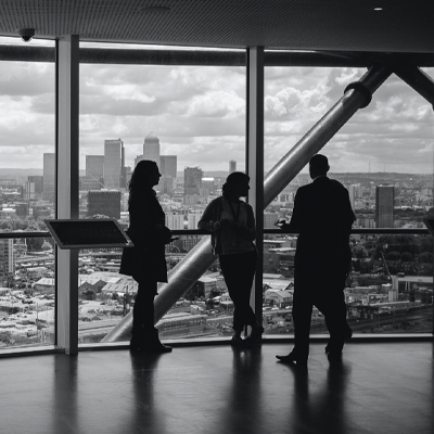three people talking to each other next to a large window