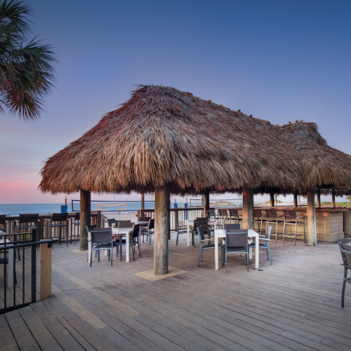 view of two tiki huts next to the ocean
