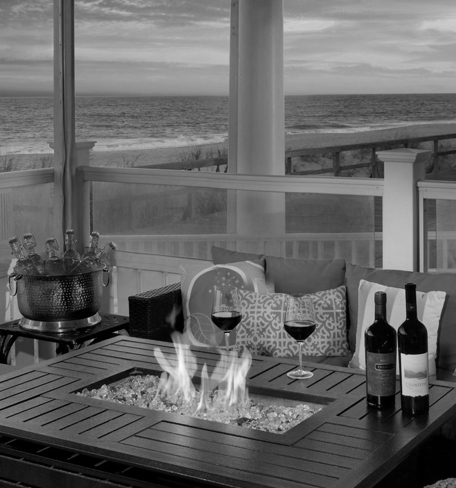 view of porch with a couch and a fire pit with wine and wine glasses