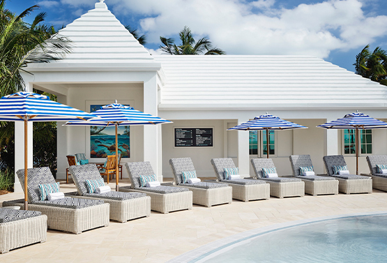 pool chairs and striped blue umbrellas by the outdoor pool at isla bella