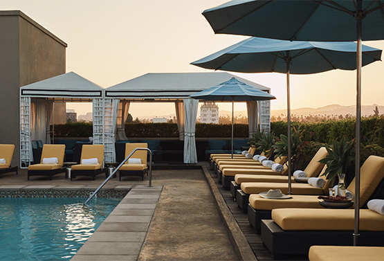 outdoor pool area at lermitage with yellow pool chairs and cabanas