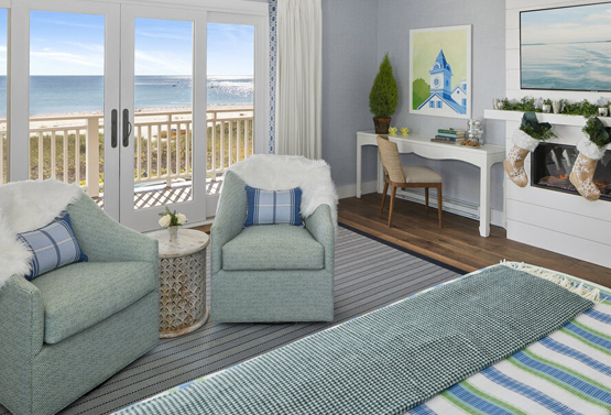 partial view of a bedroom with two blue chairs and a desk and fireplace at gooserocks beach house