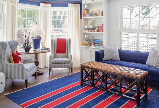 a living area with a blue couch and gray chairs and a blue and red striped rug at kennebunkport inn
