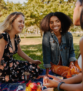 three smiling women sitting in a park