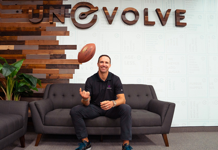 a man sitting on a couch throwing a football in the air