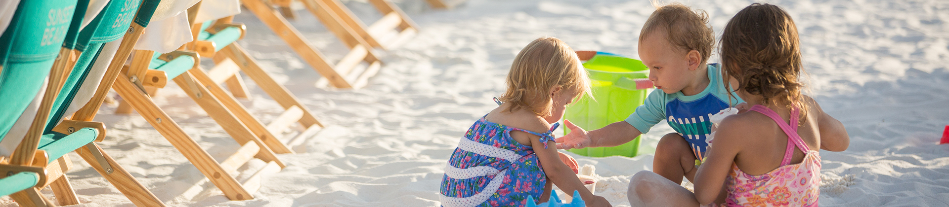 three kids playing in the sand on the beach during the day