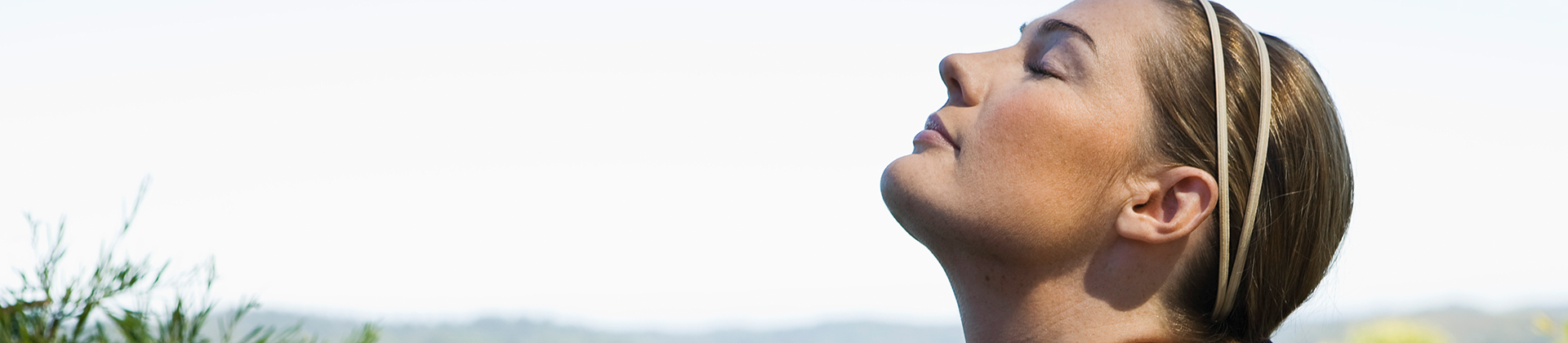 a woman with her eyes closed standing outside and her head pointing towards the sky
