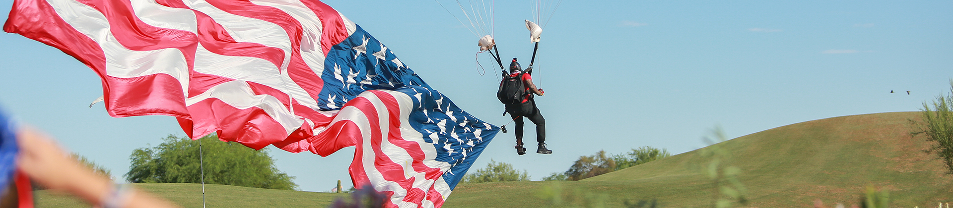 Parachuter pulling an American flag behind him