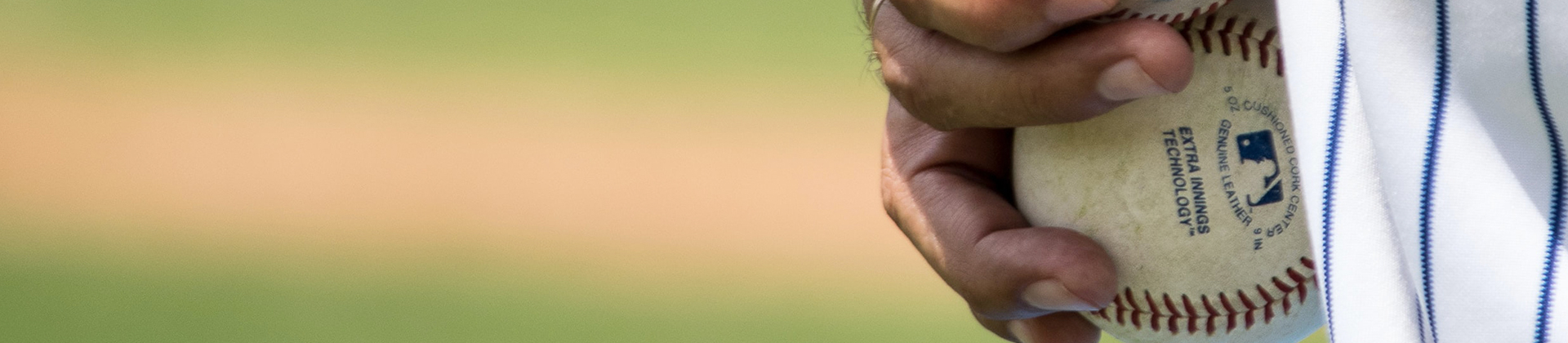 close up of a baseball pitcher holding a baseball in his hand