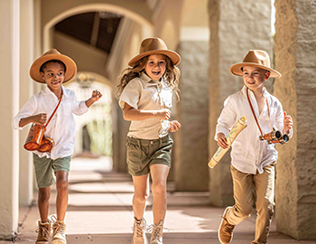 Three children dressed as explorers running together