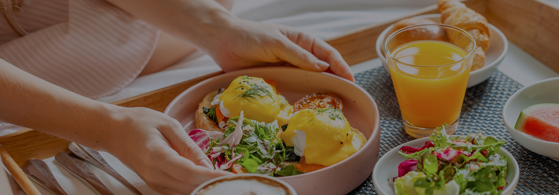 breakfast entrees and a glass of orange juice served with fresh fruit