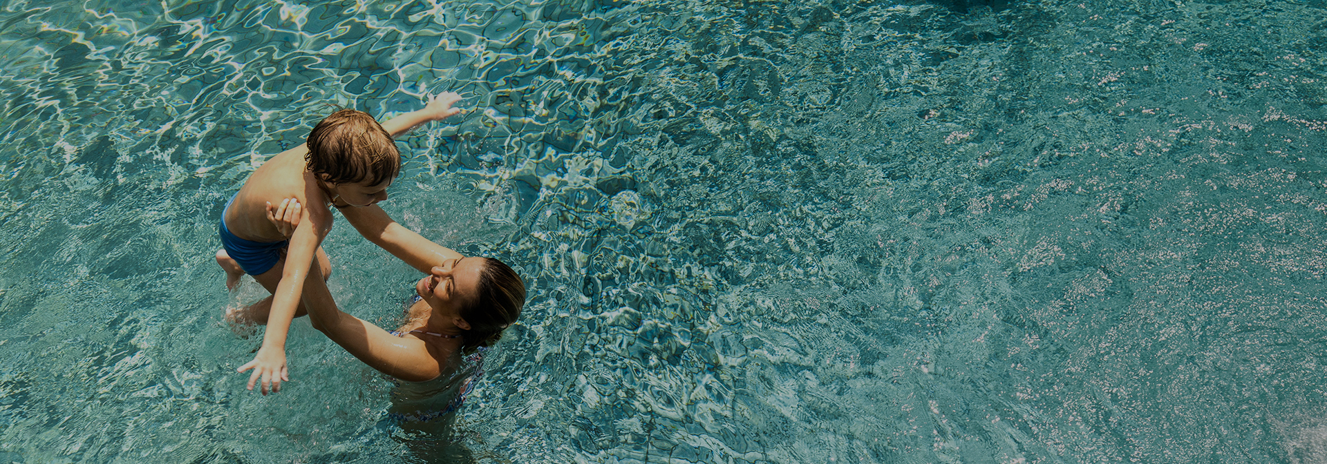a woman holding her kid above her shoulders in the pool