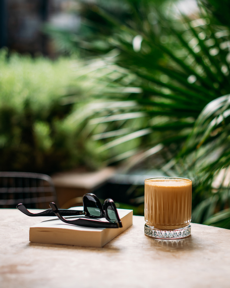 sunglasses, a book, and cocktail sitting on a table