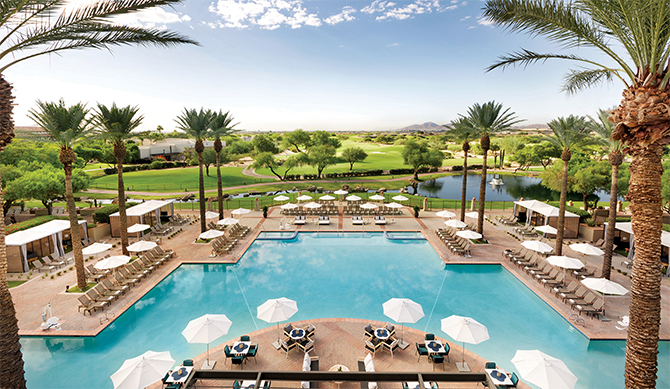 a large pool with white umbrellas on the deck and lounge chairs