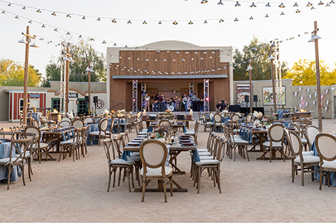 tables outside with a stage near and string lights hanging above
