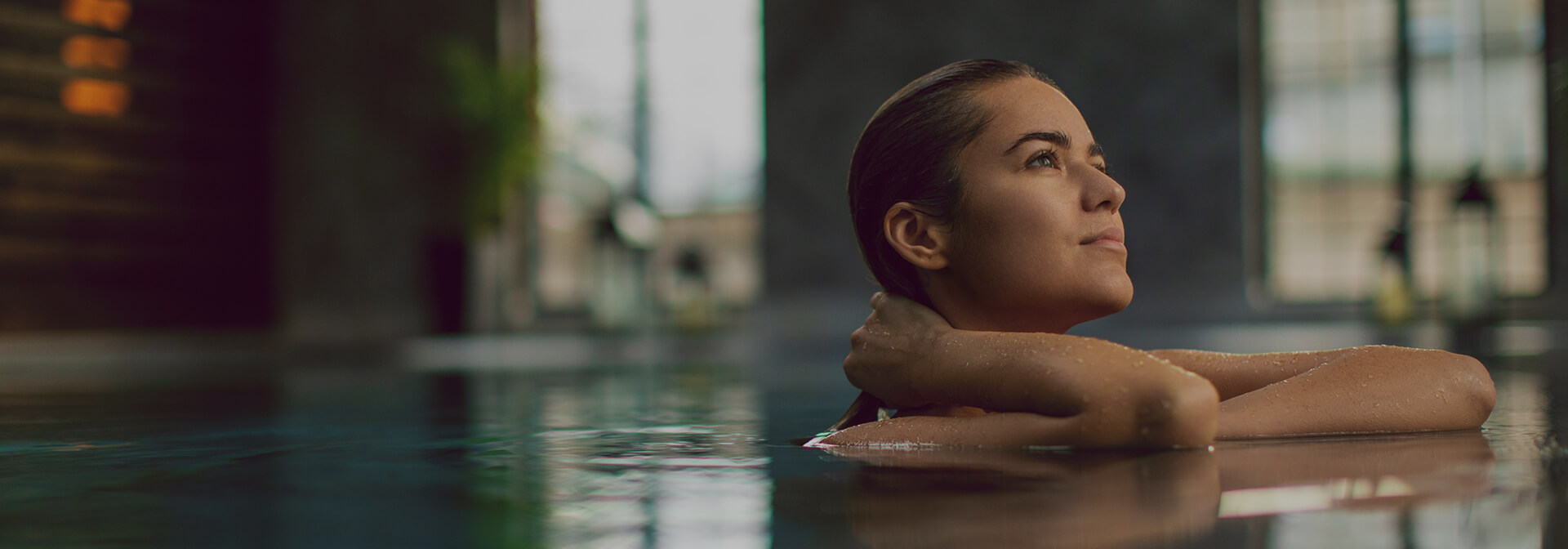 a woman in the pool looking up while her hand is in her hair