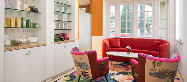room with sofa and two arm chairs with spa products sitting on a shelf