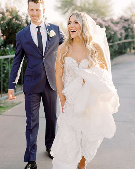 a groom holding his bride's dress off of the ground
