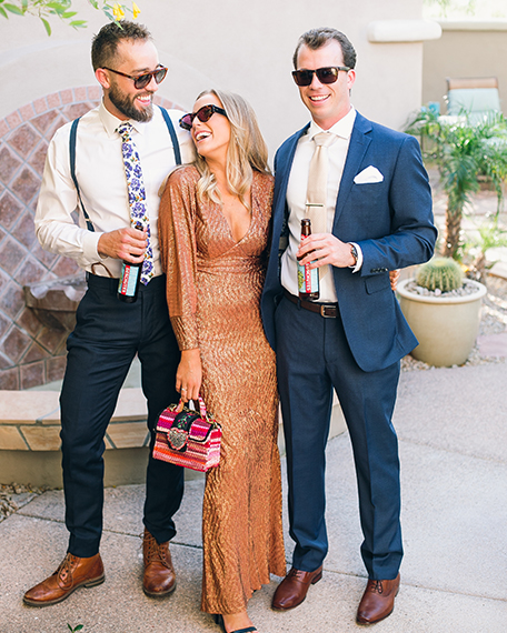two men and a woman smiling and holding drinks in their hands