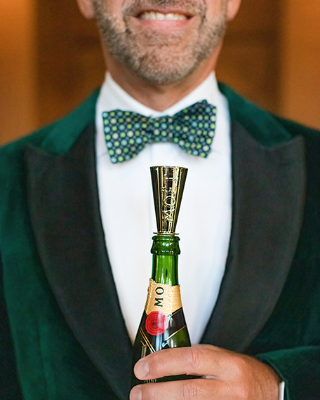 man in a green tuxedo holding a champagne bottle