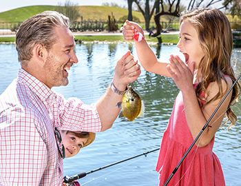 father fishing with his kids at the lake