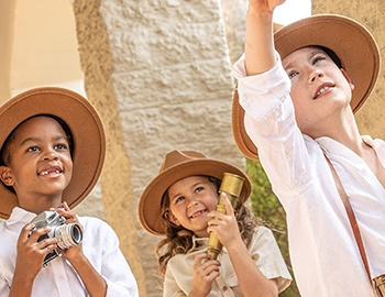 kids dressed as explorers carrying a telescope and camera