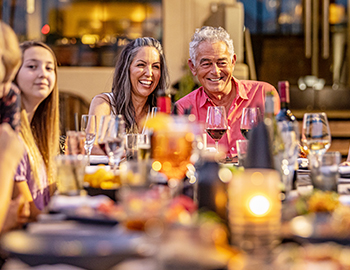 a group sitting around a dinner table laughing and having wine
