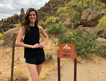 woman standing next to hiking trail sign