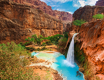 waterfall in a desert canyon pouring into a blue algoon
