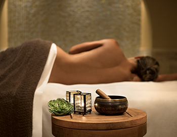 A woman laying on her side on a massage table with various items laid out on a small table