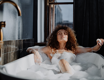 woman relaxing in a bubble bath in a large soaking tub