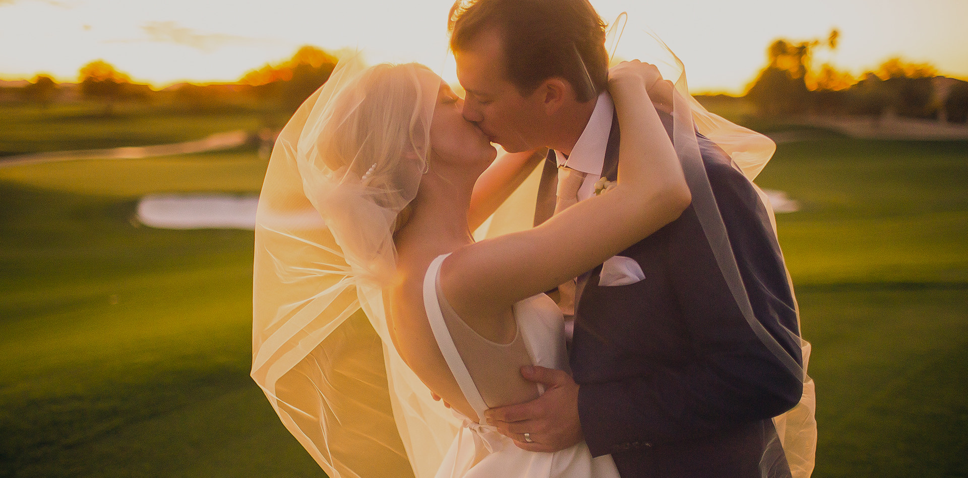 bride and groom kissing at sunset