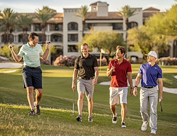 group of men walking and talking on a golf course