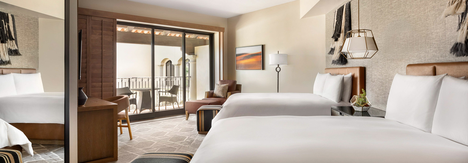 a large room with two bed and a balcony with lots of light coming in from outside
