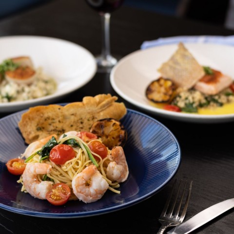 seafood dishes with a glass of wine and a cocktail