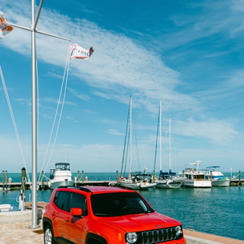 red jeep in front of flag on dock