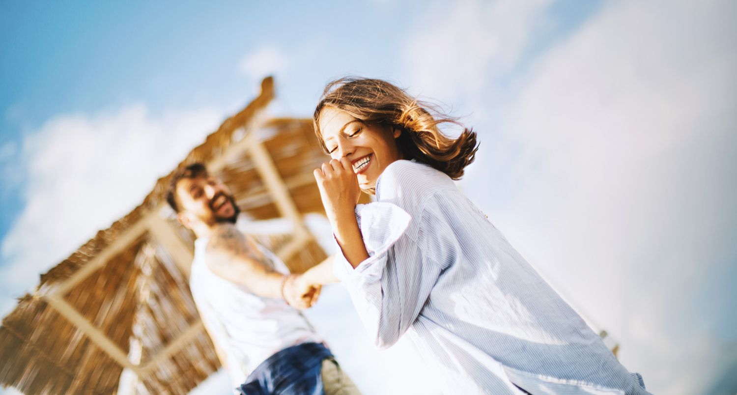 couple laughing holding hands with sky in background