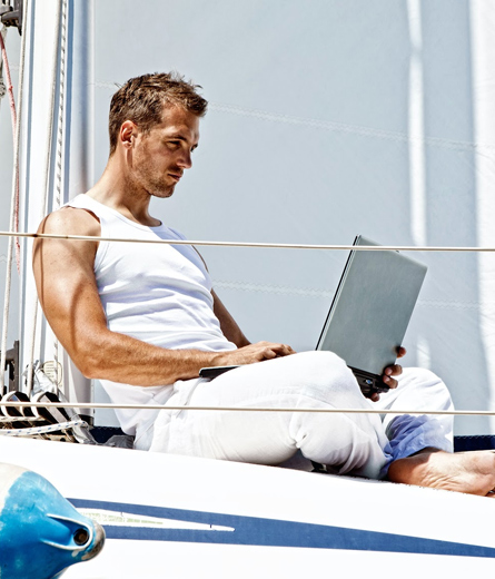 man using laptop while on a sailboat