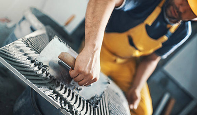 man dressed in construction attire preparing to lay tiles