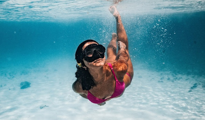 woman with a snorkel mask on swimming in clear water